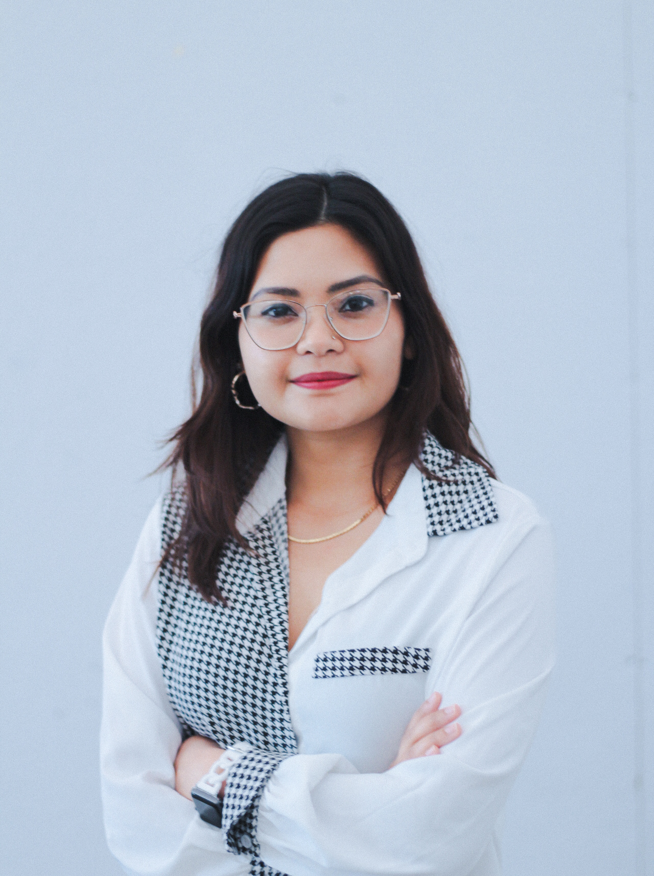 Color photograph of Herron School of Art and Design assistant professor Amrita Datta wearing glasses and shirt with patches of white and patches of a houndstooth pattern